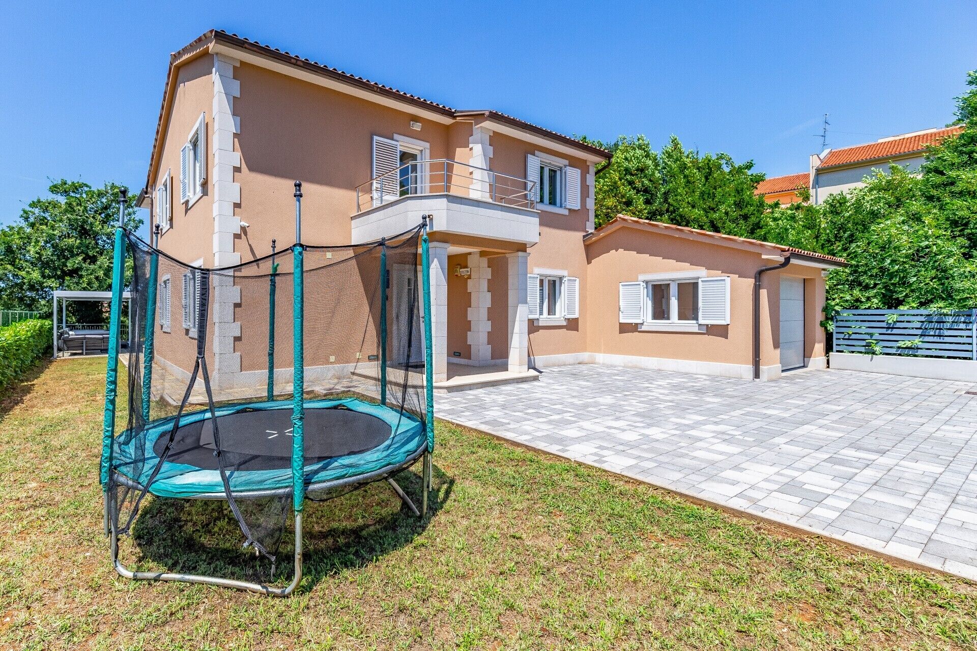 Ein zweistöckiges Haus mit einem Trampolin im Garten.