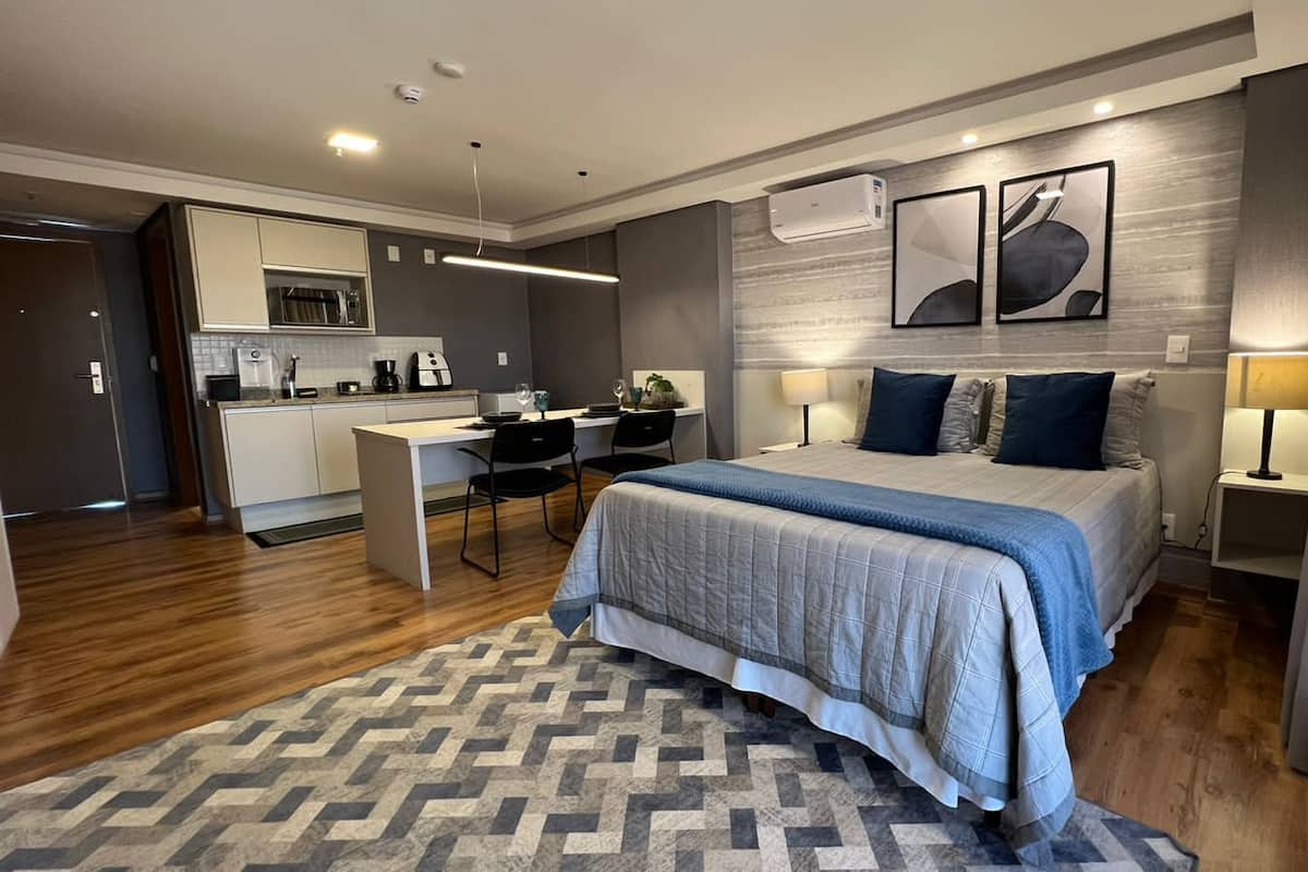 Una habitación de hotel moderna con una cama grande, un escritorio y una kitchenette.