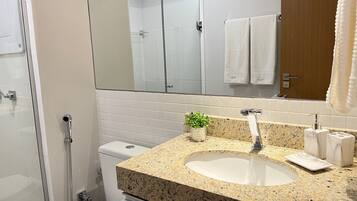 A modern bathroom with a granite countertop sink, a glass shower enclosure, and a white toilet.
