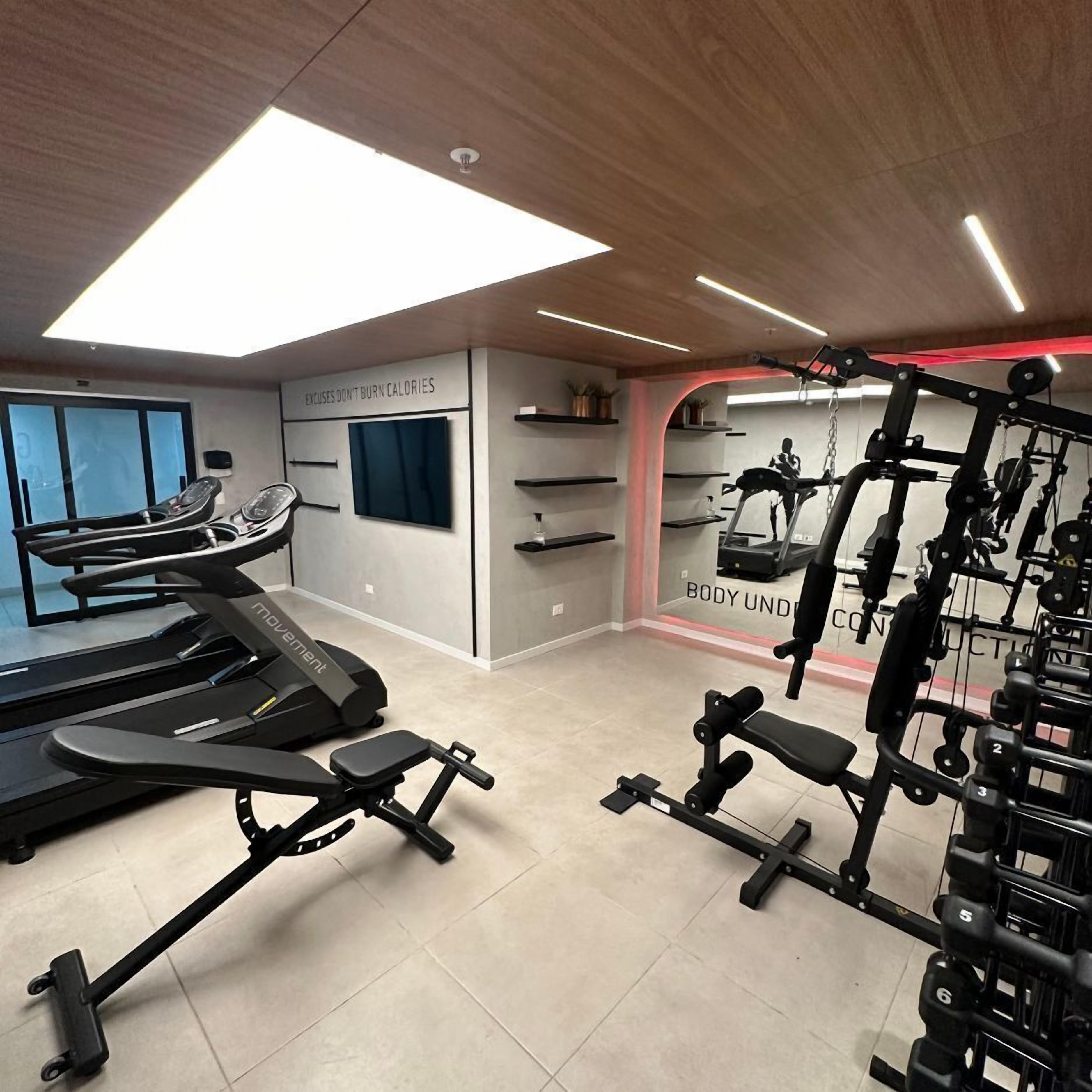 Uma academia moderna com esteira, banco de musculação e diversos equipamentos de exercício.