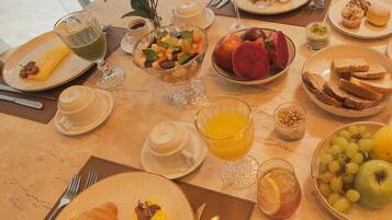 A breakfast table with various dishes including croissants, fruit, and beverages.
