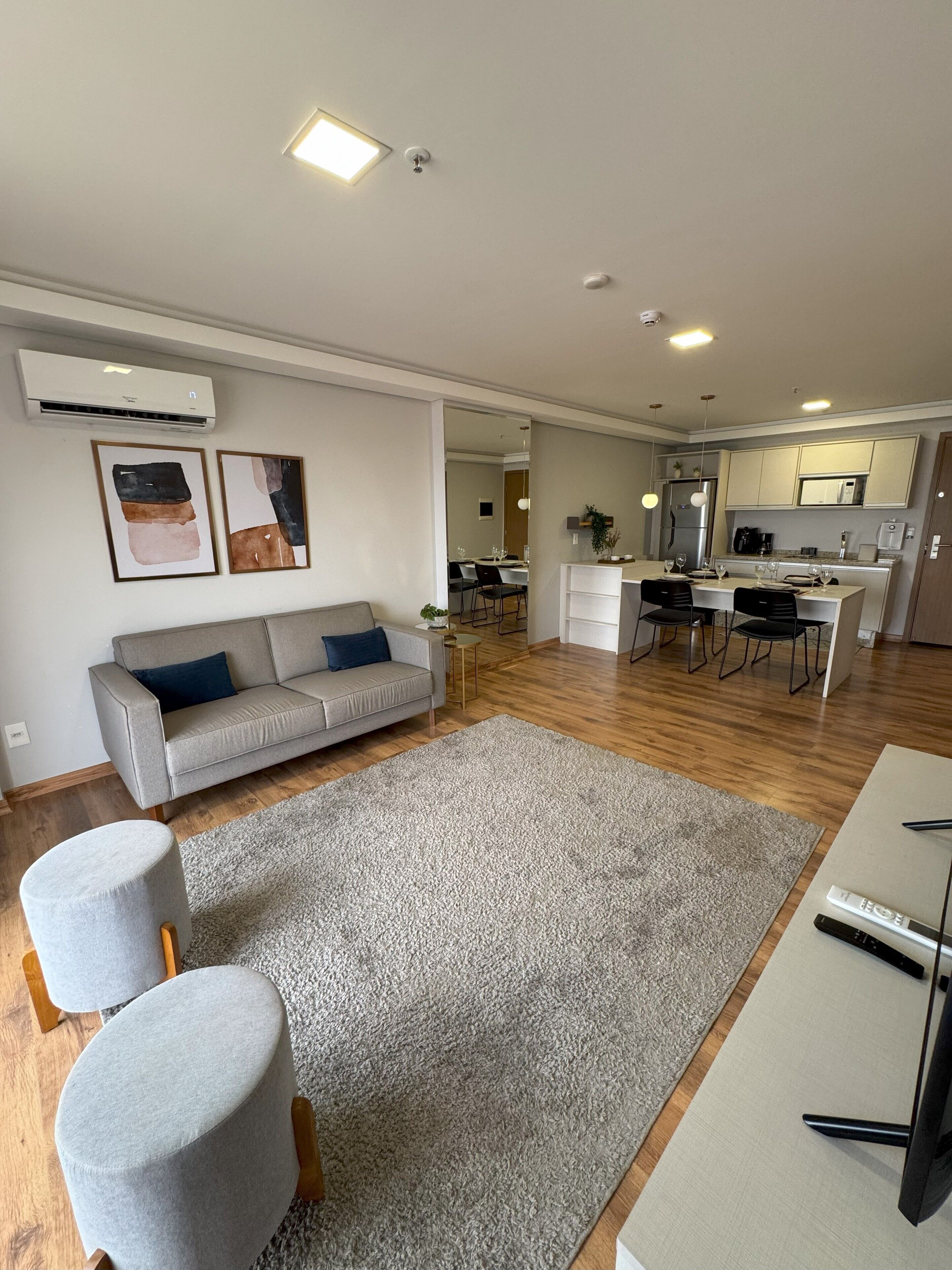 A modern living room with a grey sofa, a grey rug, and a dining area with a table and chairs.