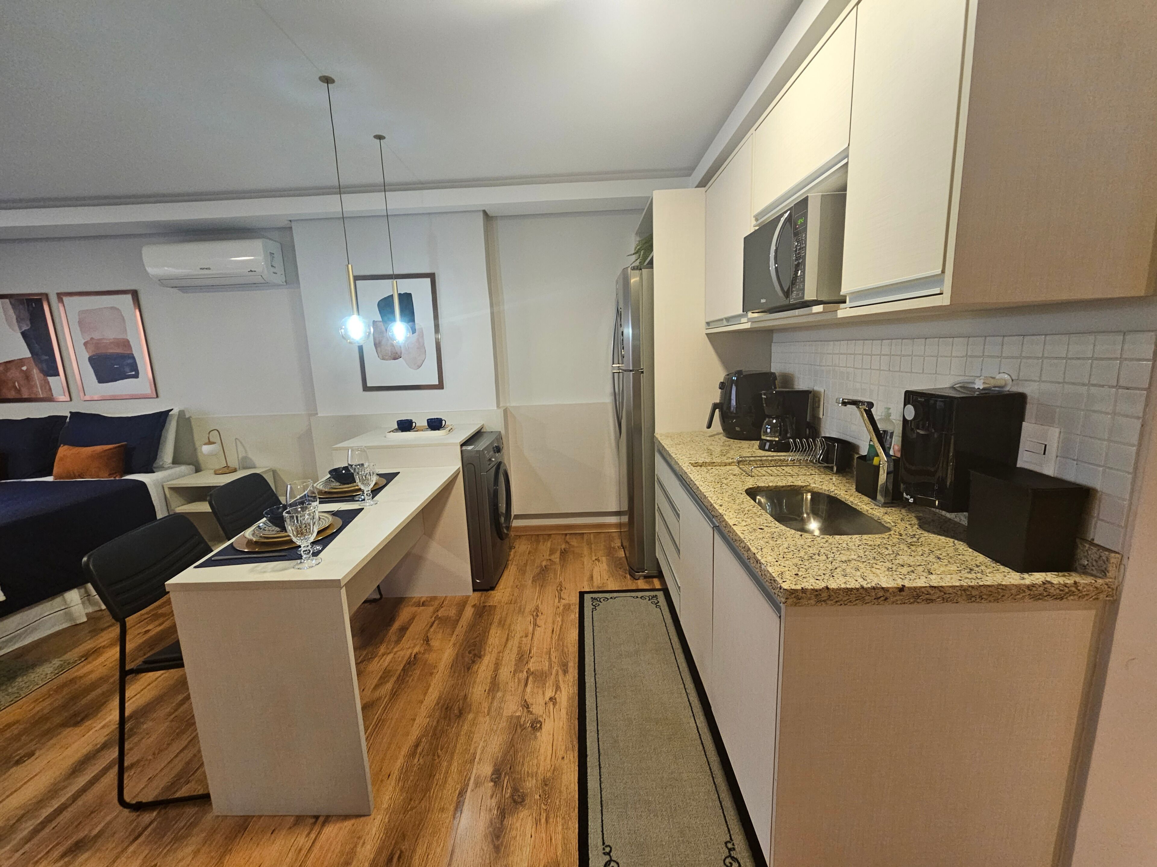 A compact kitchen with a central island, a microwave, a coffee maker, and a sink.