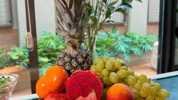 Un tazón de madera lleno de frutas y una piña sobre una mesa.