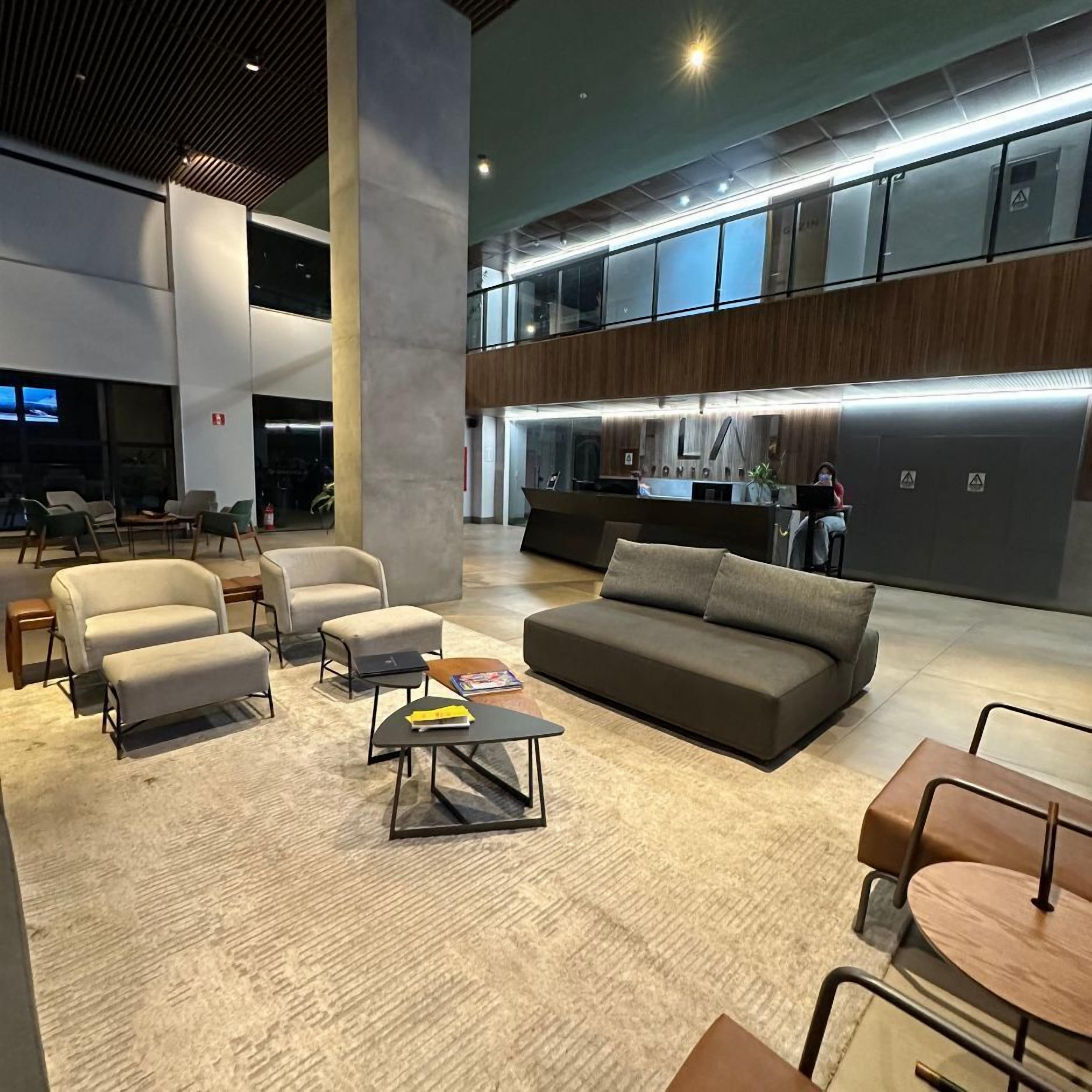 A modern lobby with a reception desk, seating area, and large windows.