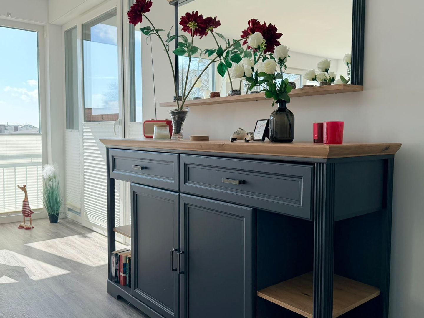 Eine moderne Küche mit einem dunklen Schrank, einer Holz Arbeitsplatte und einer Vase mit Blumen.
