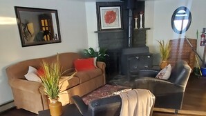 Ein geräumiges Wohnzimmer mit Kamin, einer Couch, einem Couchtisch und einer Topfpflanze.