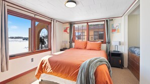 Un dormitorio con una cama grande, dos mesitas de noche y un ventanal con cortinas.