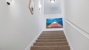 A carpeted staircase with a picture of a wooden pier on the wall. - Stylish Family Townhouse in Baton Rouge LA- BC1004 (Baton Rouge)
