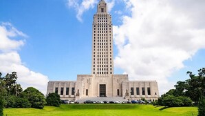 A large, rectangular building with a central tower and symmetrical wings, surrounded by a well-maintained lawn and trees. - Stylish Family Townhouse in Baton Rouge LA- BC1004 (Baton Rouge)