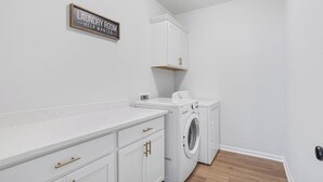 A laundry room with white cabinetry, a washing machine, and a dryer. - Stylish Family Townhouse in Baton Rouge LA- BC1004 (Baton Rouge)