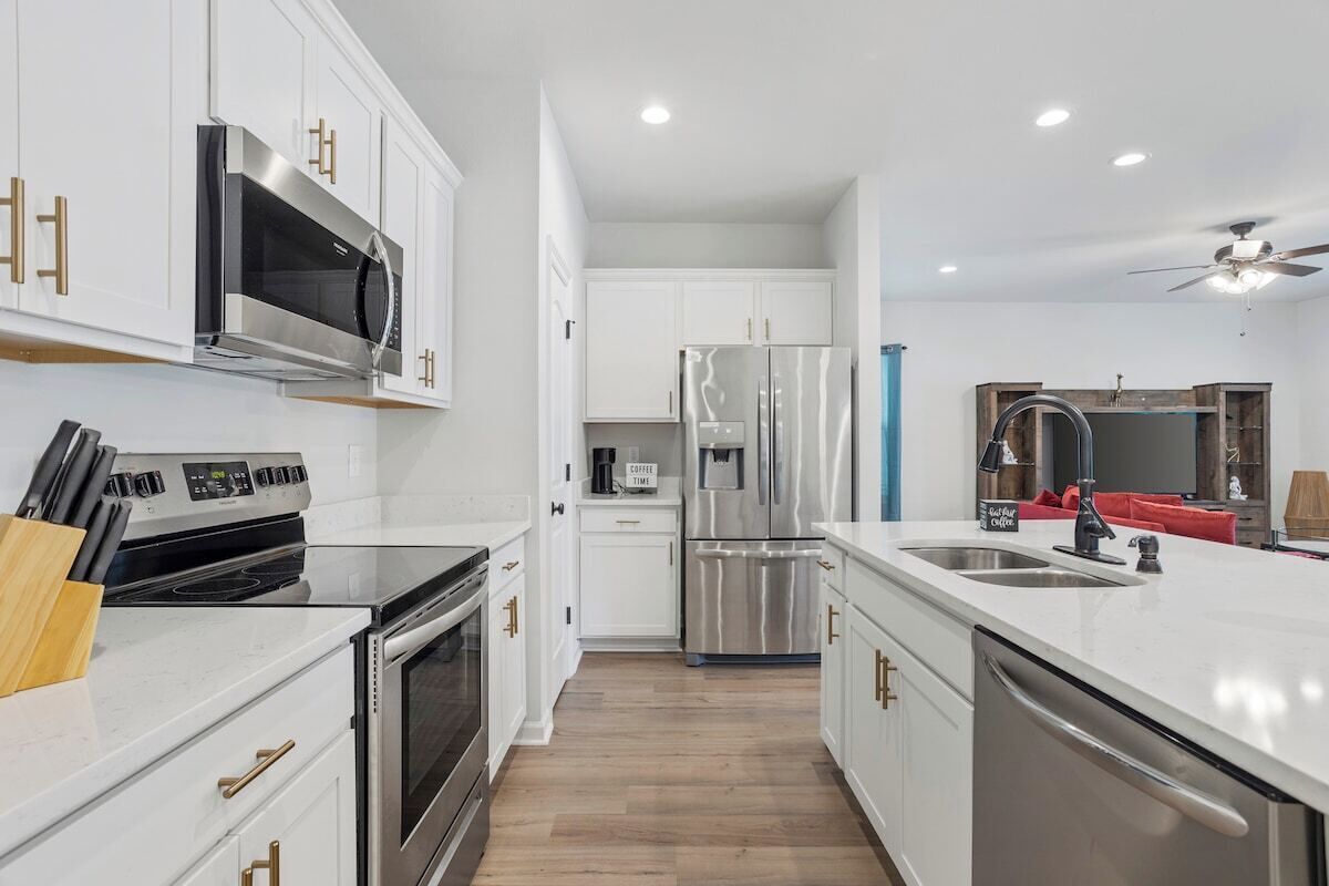 A modern kitchen with white cabinetry, stainless steel appliances, and a central island with a sink.
