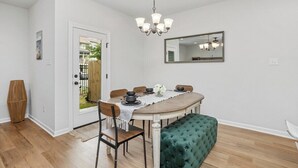 A dining area with a round table, chairs, a bench, a chandelier, and a mirror on the wall. - Stylish Family Townhouse in Baton Rouge LA- BC1004 (Baton Rouge)