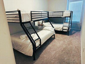 A room with bunk beds, carpeted floor, and a window with blinds. - Stylish Family Townhouse in Baton Rouge LA- BC1004 (Baton Rouge)
