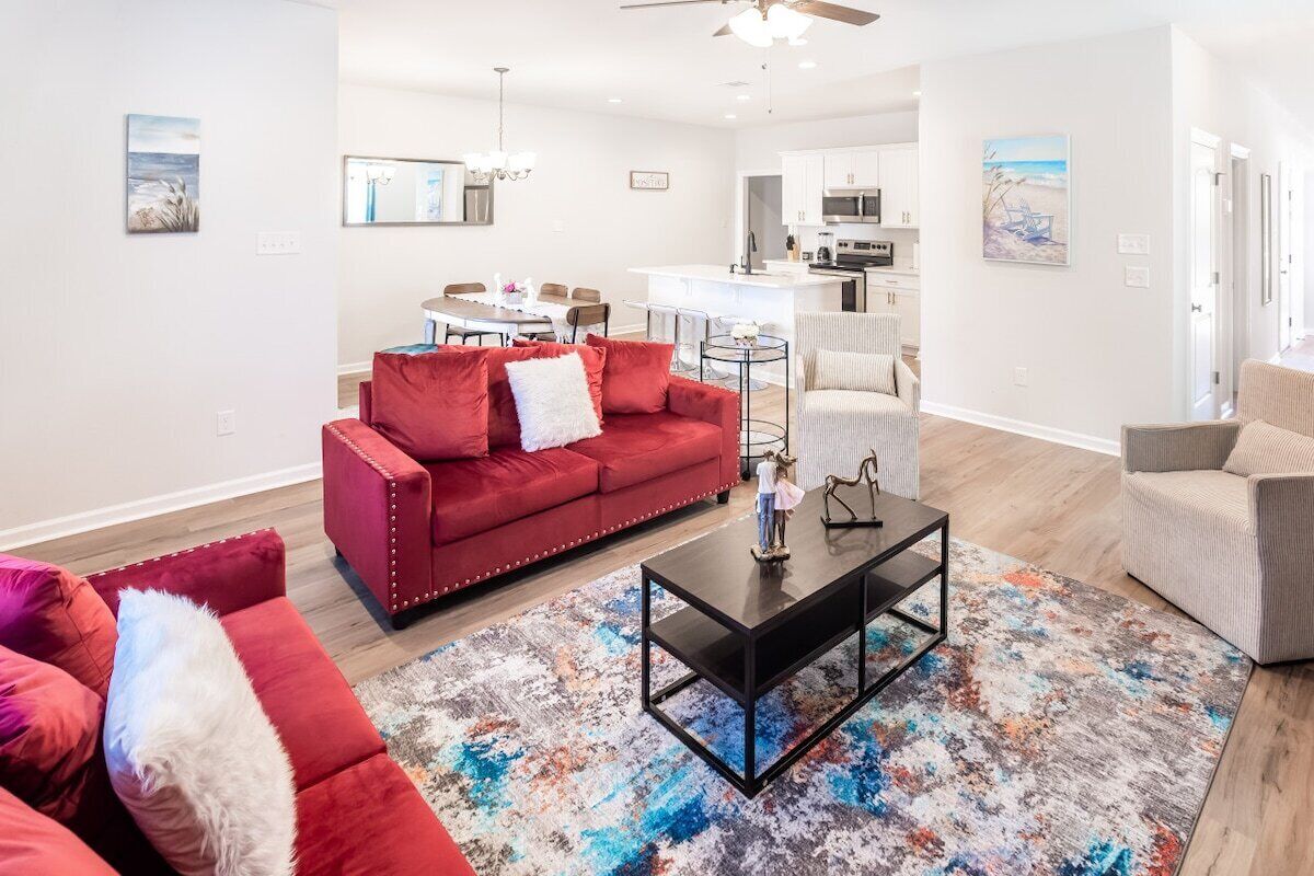 A modern living room with a red sofa, a coffee table, and a colorful rug.