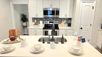A modern kitchen with white cabinets, a stainless steel sink, and a black stove.