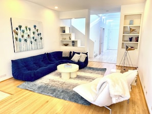 Relax in this stylish living room with a blue sofa, round coffee table, and armchair, surrounded by a beautiful painting and decorative items.