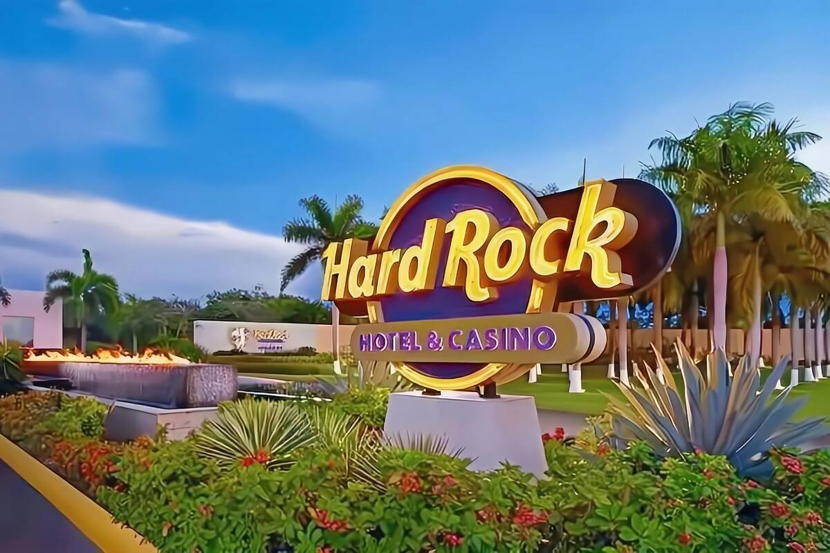 A Hard Rock Hotel & Casino sign with a neon outline, surrounded by tropical landscaping and palm trees.