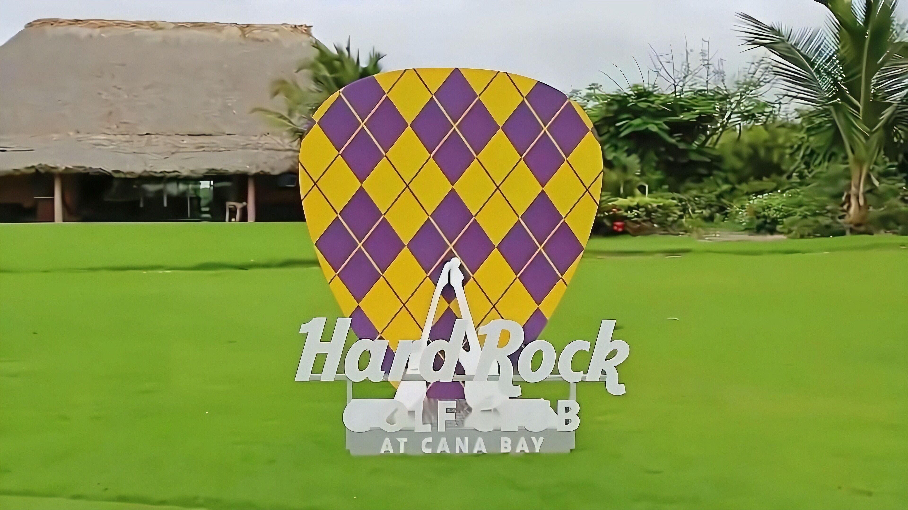 A hot air balloon with a diamond pattern, standing on a green lawn.
