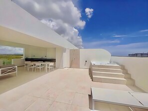 Um terraço no último andar com área de refeições, cozinha e vista para a paisagem.