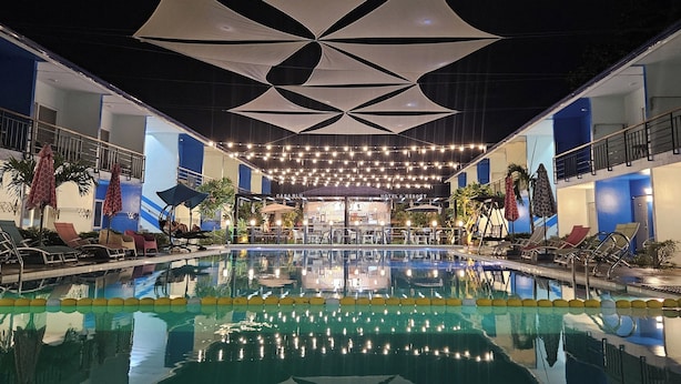 Ein Hotelpoolbereich mit Liegestühlen, Sonnenschirmen und einem geometrischen Deckenmuster.