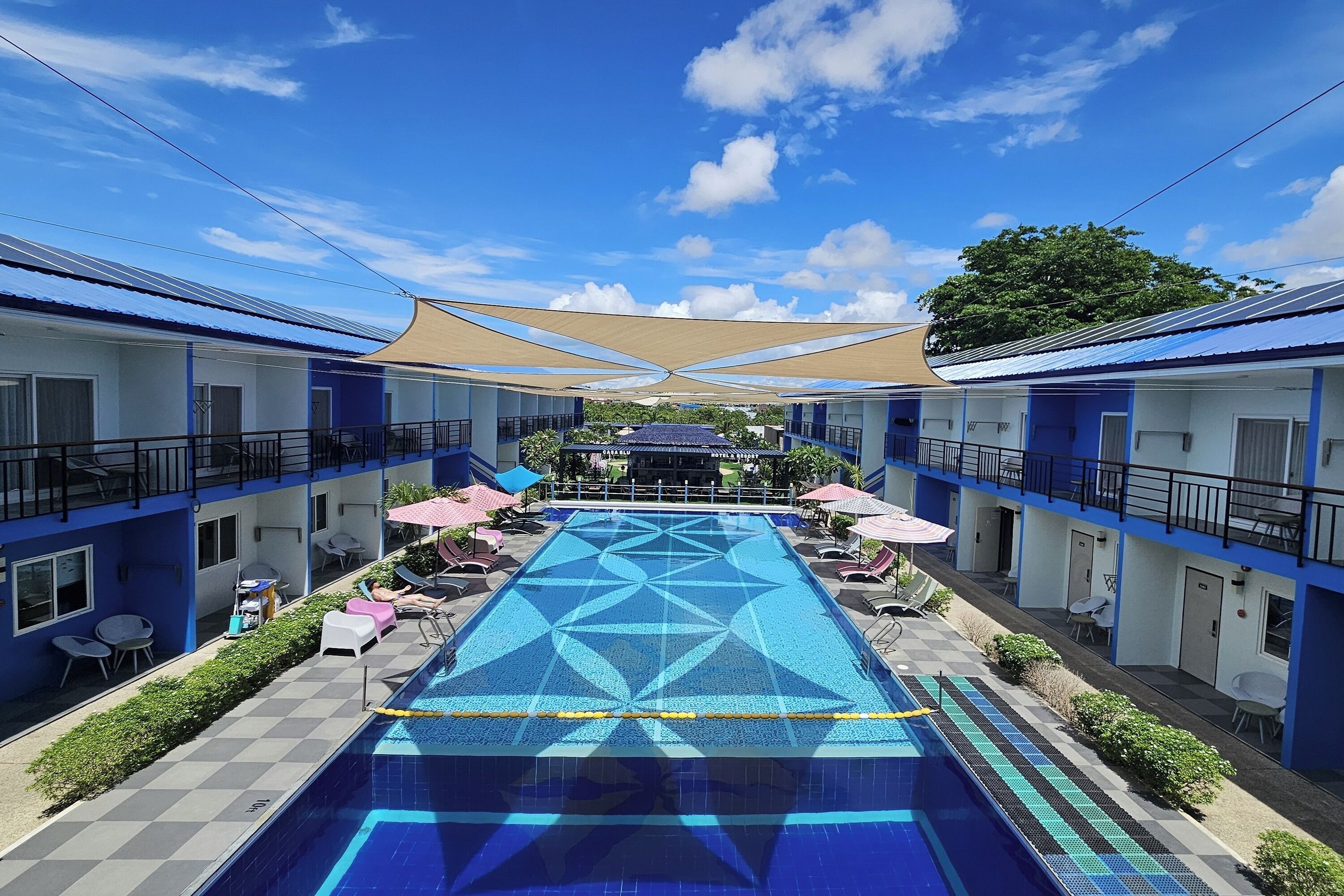 Un hotel con piscina, zona de estar al aire libre y espacio cubierto.