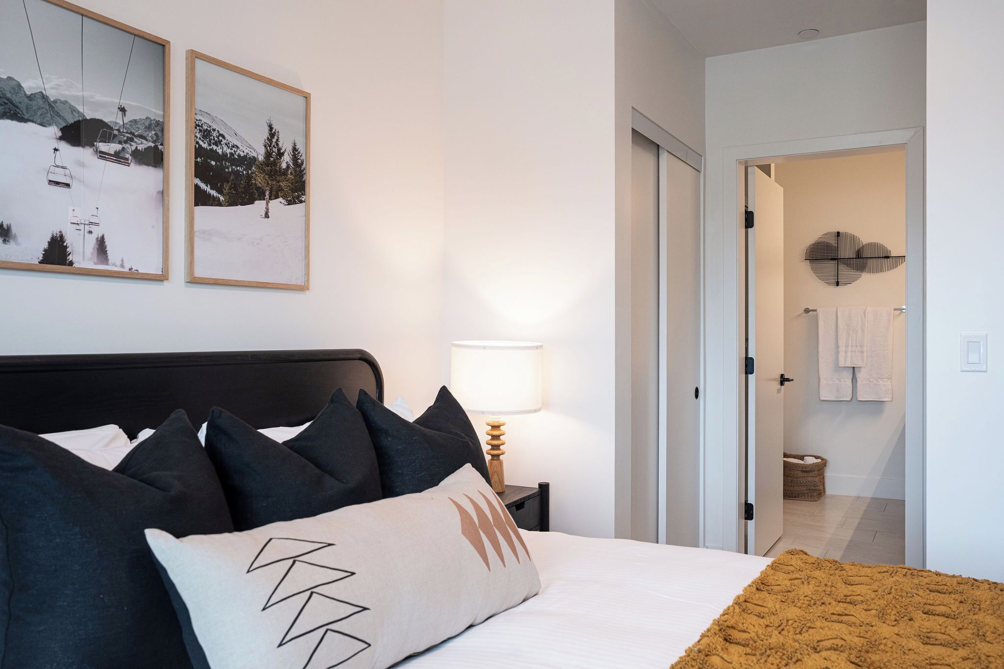 A hotel room with a bed, a nightstand with a lamp, and two framed pictures on the wall.