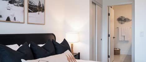 A hotel room with a bed, a nightstand with a lamp, and two framed pictures on the wall.