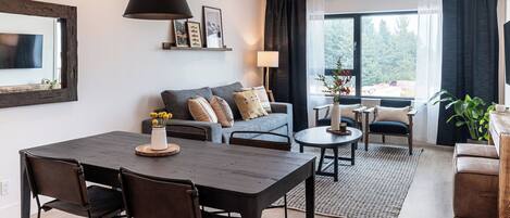 A modern living room with a dining area, featuring a sofa, coffee table, and chairs.