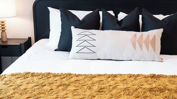 A neatly made bed with a patterned blanket, a black headboard, and multiple pillows.