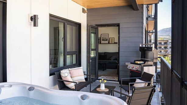 Ein Balkon mit Whirlpool, Sitzgelegenheit und Grill.