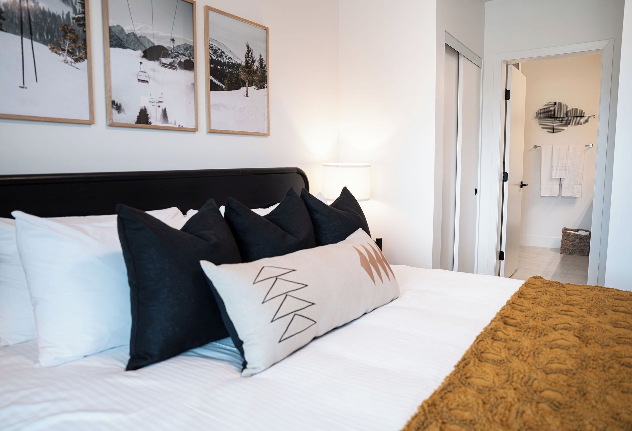 A neatly made bed with a variety of pillows, a headboard, and a blanket.