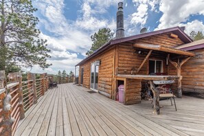 Eine Holzhütte mit einer Terrasse, einem Schornstein und einer Satellitenschüssel.
