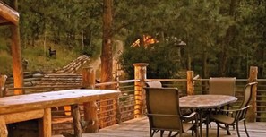 Eine Terrass mit Holzmöbeln und Geländer, umgeben von Bäumen.