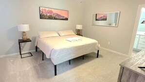 A bedroom with a bed, two bedside tables, a ceiling fan, and a painting on the wall. - Retreat at Louisiana State Capitol by LSU - CB1016 (Baton Rouge)