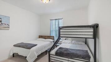 A bedroom with two single beds, a window with curtains, and a painting on the wall.