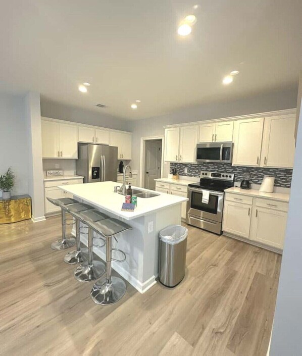 A modern kitchen with a central island, stainless steel appliances, and a bar stool seating area.