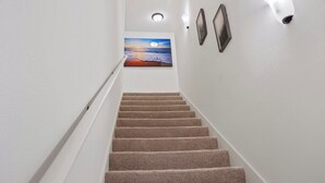 A carpeted staircase with a painting of a sunset on the wall. - Retreat at Louisiana State Capitol by LSU - CB1016 (Baton Rouge)