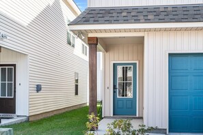 Une maison à deux étages avec une porte d’entrée bleue, une porte de garage et un porche couvert.