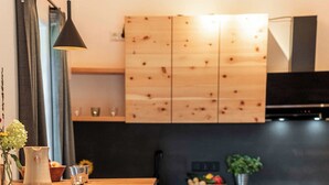 A modern kitchen with wooden cabinets, a stainless steel oven, and a bar stool. - Apartment "Georg" 43 sqm with balcony (Traunstein)