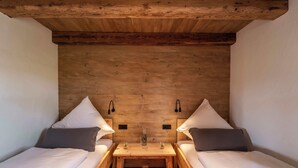 Una habitación acogedora con dos camas individuales, una mesa de madera y dos lámparas de pared.