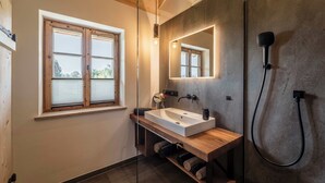 A modern bathroom with a wooden vanity, a large mirror, and a shower.