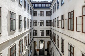 Ein mehrstöckiges Gebäude mit Innenhof, versehen mit einer Reihe von Fenstern auf jeder Etage.