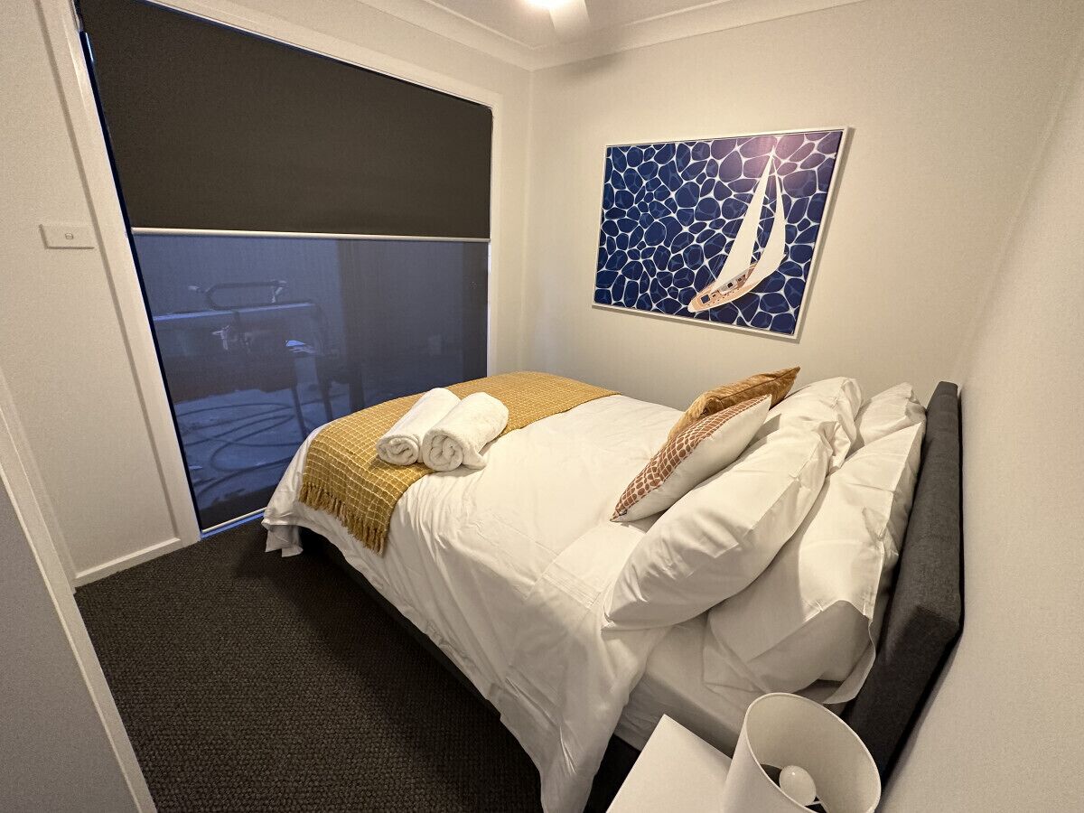 Une chambre d’hôtel avec un lit, un tableau et une vue sur un bateau, visible par la fenêtre.