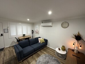 A modern living room with a dark blue sofa, a round coffee table, and a small side table with decorative items.