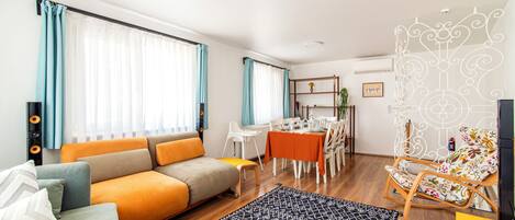 A modern living room with a sofa, dining table, and a decorative chair.