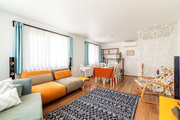 A modern living room with a sofa, dining table, and a decorative chair.