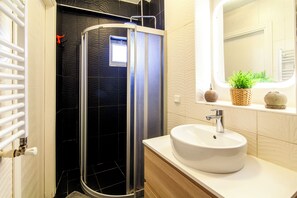 A modern bathroom with a glass shower enclosure, a white sink, and a mirror above the sink.