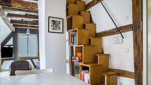 Une pièce avec une bibliothèque en bois, un tableau encadré au mur et une fenêtre donnant sur un beau paysage.