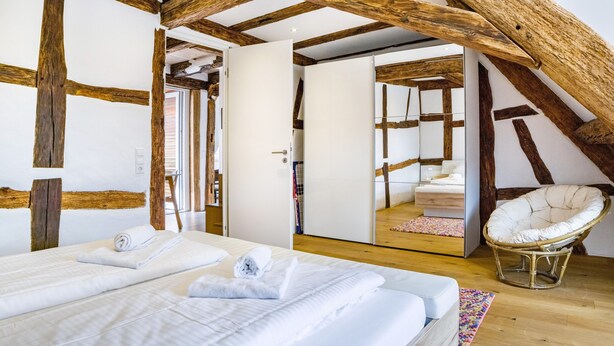 Une chambre avec un grand lit, une chaise et un plafond en bois.